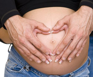 A woman and man's hands holding her stomach caringly.